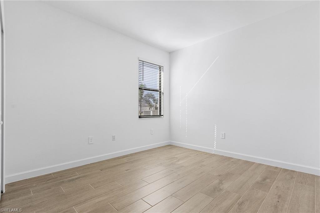 20662 Greenwich Place Estero, FL 33928 - Photo 17 of 26 an empty room with wooden floor and windows