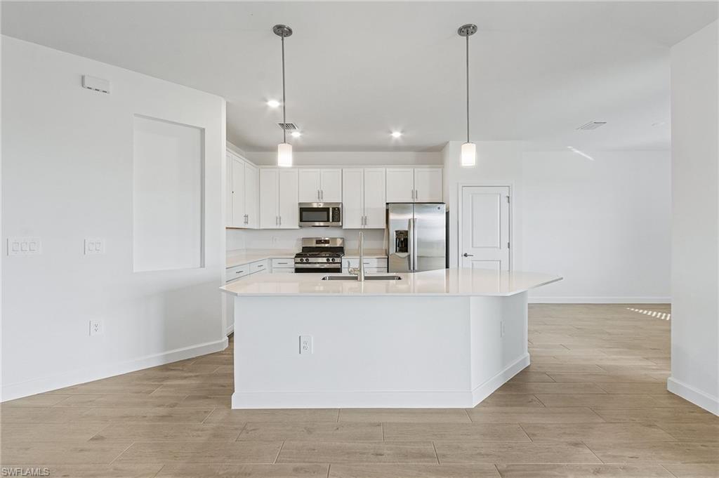 20662 Greenwich Place Estero, FL 33928 - Photo 9 of 26 a large kitchen with stainless steel appliances a refrigerator a stove a sink and a chandelier