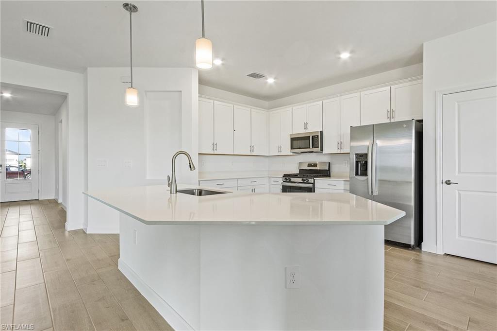 20662 Greenwich Place Estero, FL 33928 - Photo 10 of 26 a large kitchen with kitchen island a sink stainless steel appliances and cabinets