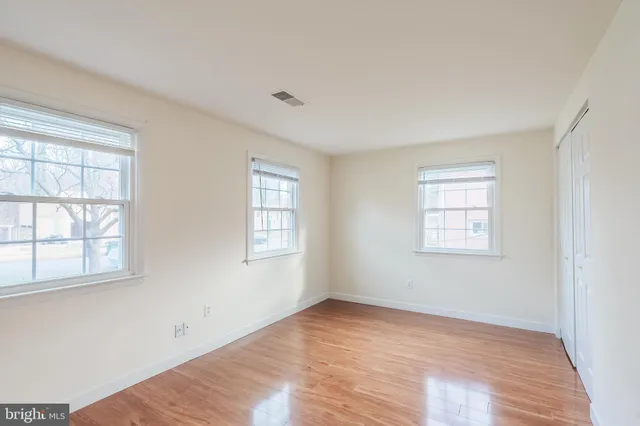 an empty room with wooden floor and windows