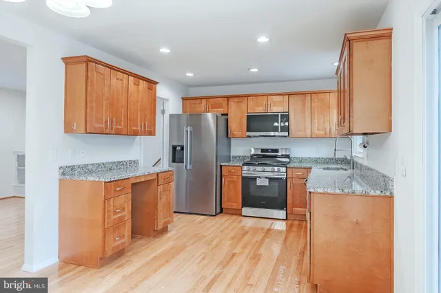 a kitchen with stainless steel appliances granite countertop a refrigerator stove top oven and sink