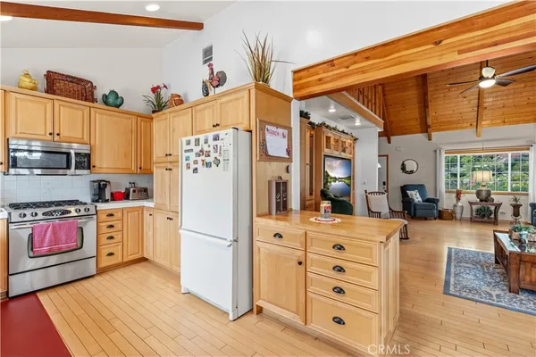 a kitchen with stainless steel appliances granite countertop a refrigerator a oven and white cabinets with wooden floors