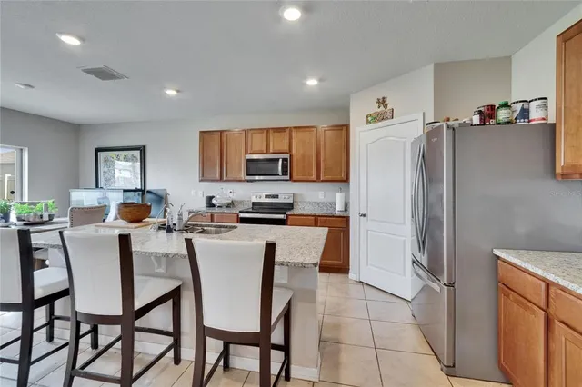 a kitchen with stainless steel appliances granite countertop a stove top oven a sink a dining table and chairs