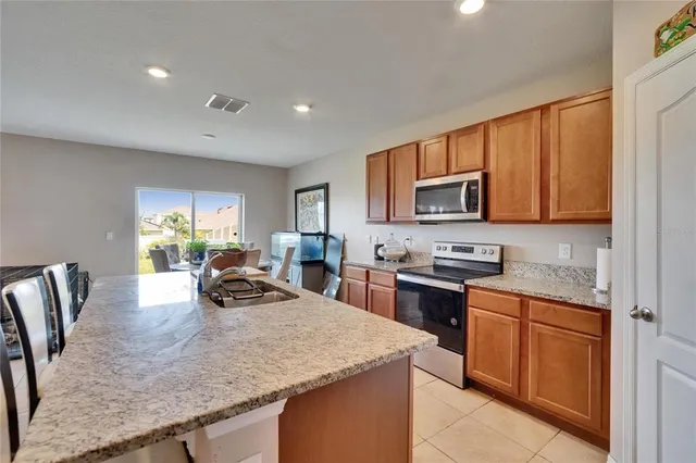 a kitchen with stainless steel appliances granite countertop a sink dishwasher stove and microwave with wooden cabinets