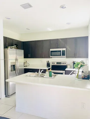 a kitchen with stainless steel appliances a stove a microwave a sink a refrigerator and cabinets