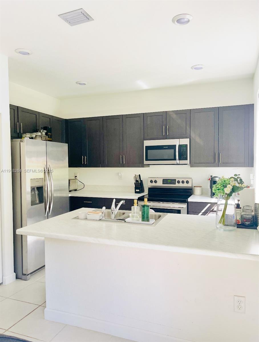2624 Southeast 11th Court, Unit 2624 Homestead, FL 33035 - Photo 6 of 19 a kitchen with stainless steel appliances a stove a microwave a sink a refrigerator and cabinets