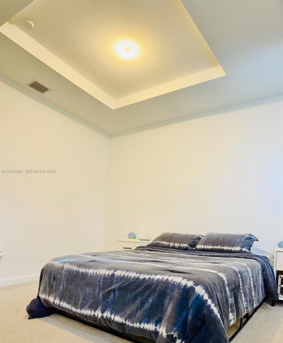 2624 Southeast 11th Court, Unit 2624 Homestead, FL 33035 - Photo 9 of 19 a bedroom with a bed and a night stand