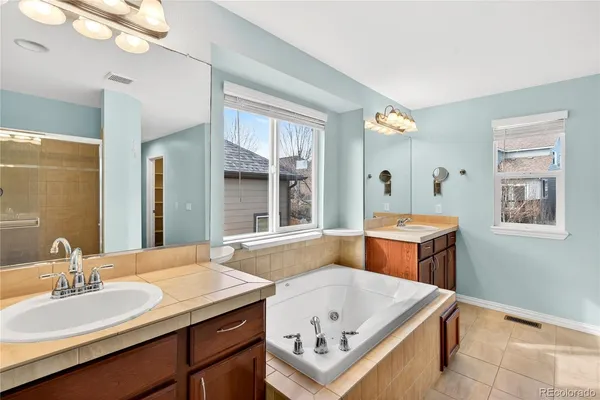 a spacious bathroom with a tub sink and mirror