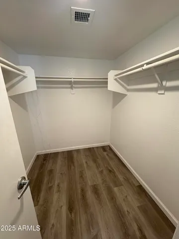 an empty room with wooden floor and fan