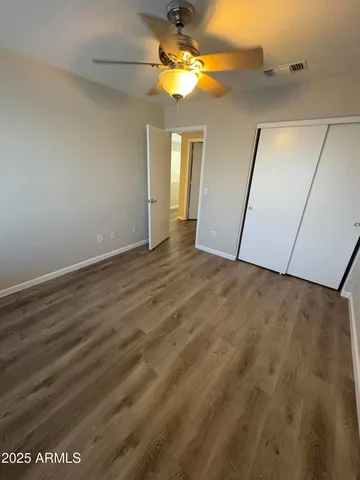 an empty room with wooden floor fan and windows