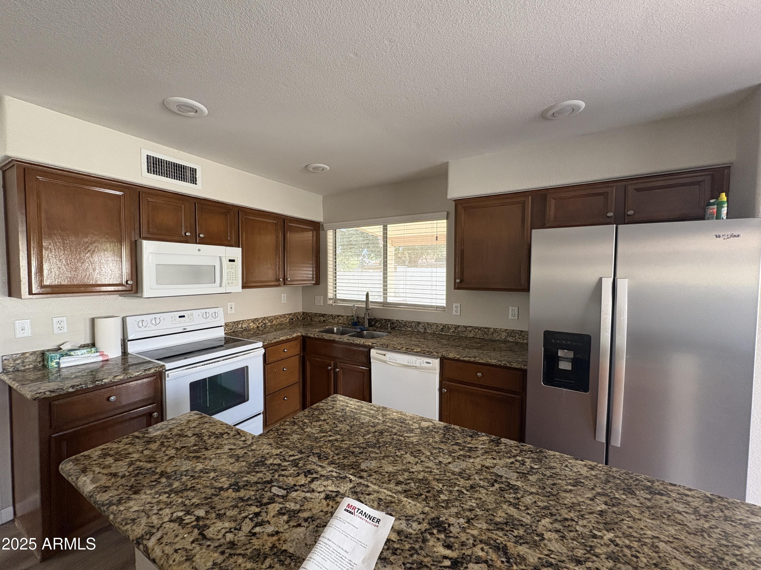 1472 East Constitution Drive Chandler, AZ 85225 - Photo 4 of 27 a kitchen with kitchen island granite countertop a refrigerator stove top oven and sink