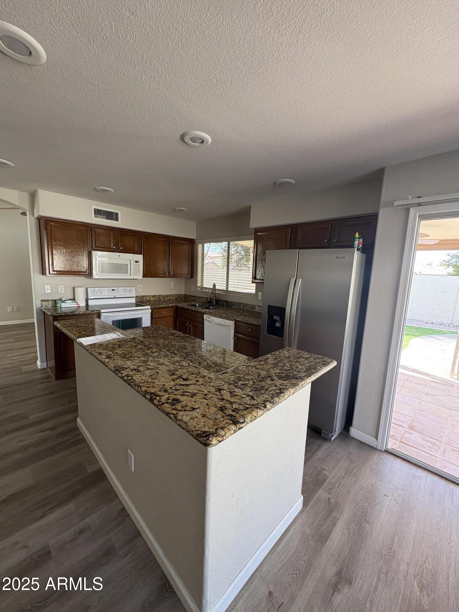 1472 East Constitution Drive Chandler, AZ 85225 - Photo 5 of 27 a kitchen with stainless steel appliances granite countertop a stove a sink and a refrigerator