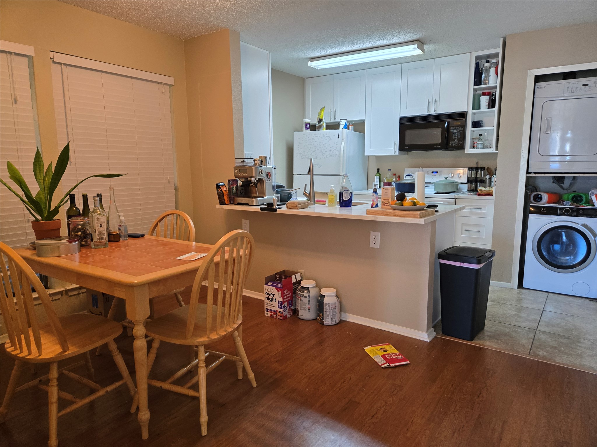3115 Helms Street, Unit 212 Austin, TX 78705 - Photo 8 of 15 a kitchen with a table chairs refrigerator and microwave