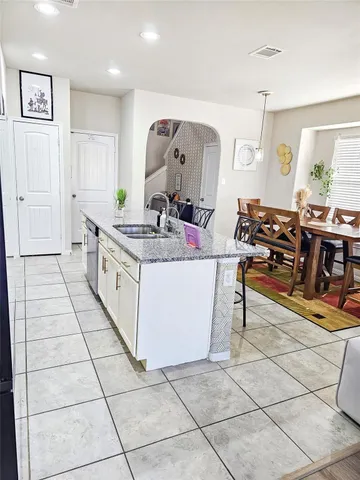 a living room with stainless steel appliances kitchen island granite countertop a sink and cabinets