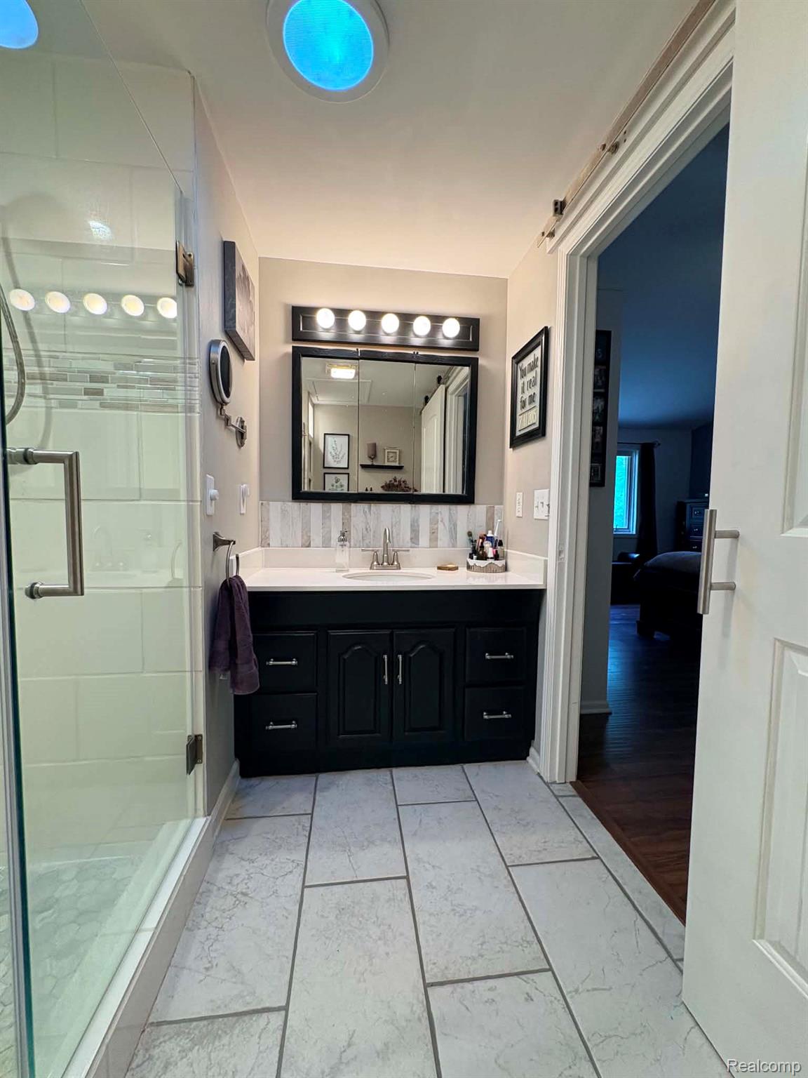 2159 East Bevens Road Caro, MI 48723 - Photo 24 of 38 Bathroom featuring a glass-enclosed shower, a dark wood vanity with a white countertop, and a tiled backsplash