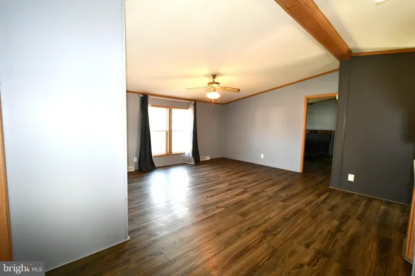 a view of an empty room with window and wooden floor