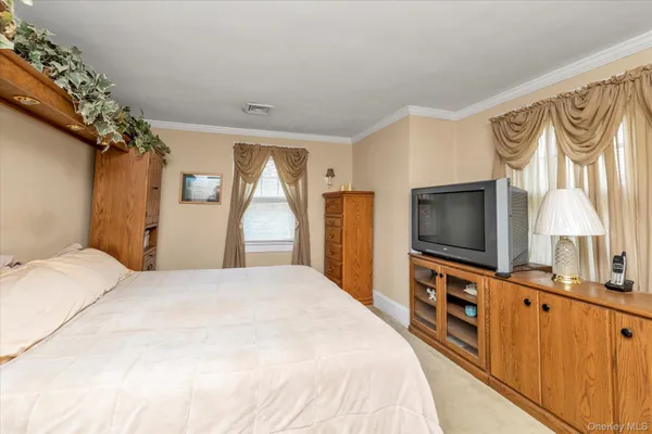 a large bedroom with a bed and a flat tv screen on dresser