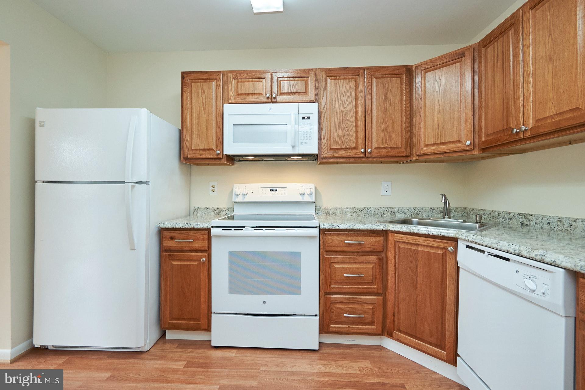 2212 Springwood Drive, Unit 206 Reston, VA 20191 - Photo 20 of 46 a kitchen with stainless steel appliances granite countertop a refrigerator stove a sink and dishwasher with wooden floor