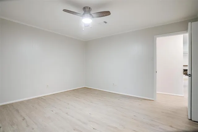 an empty room with wooden floor ceiling fan and windows