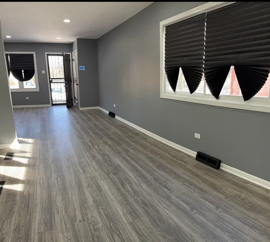 a view of an empty room with wooden floor and windows