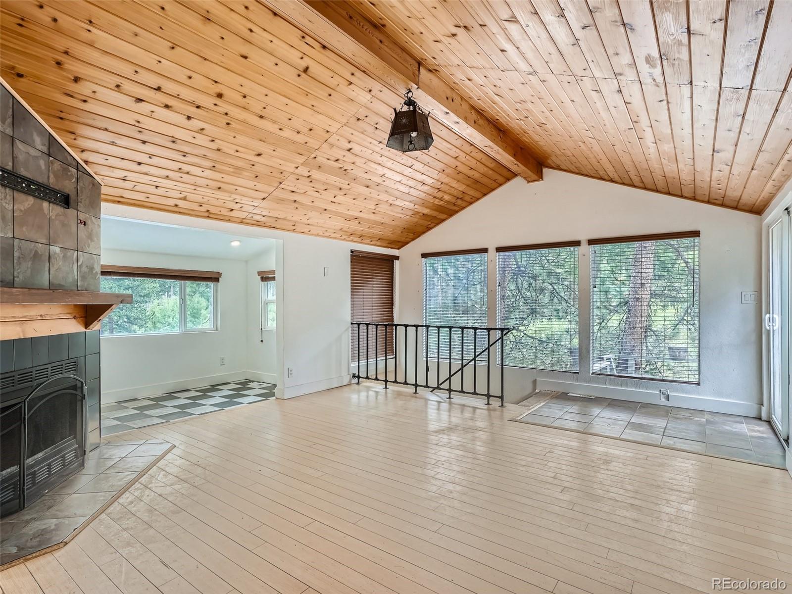 11799 Ranch Elsie Road Golden, CO 80403 - Photo 4 of 28 an empty room with wooden floor and fireplace