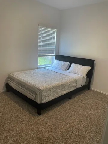 a bed sitting in a spacious bedroom next to a window