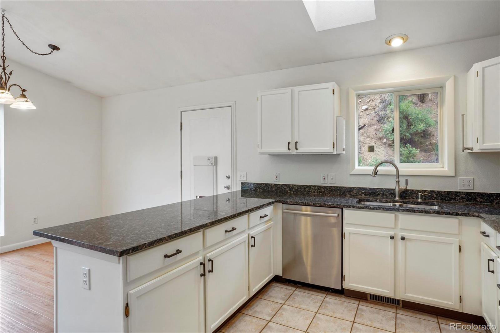 13519 Elsie Road Conifer, CO 80433 - Photo 7 of 31 a kitchen with granite countertop white cabinets white appliances and a sink