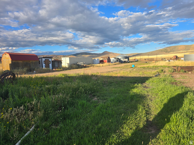 34200 Coulam Road Swan Lake, ID 83281 - Photo 15 of 24 Expansive land featuring a grassy foreground, multiple outbuildings, and a mountainous backdrop
