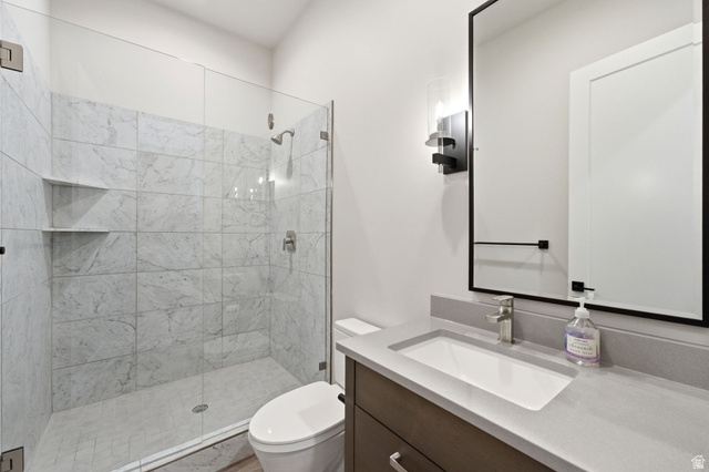 496 North Farmhouse Way, Unit 11 Midway, UT 84049 - Photo 29 of 50 Bathroom featuring a glass-enclosed shower with tiled walls and built-in shelving, a contemporary vanity with an integrated sink and light grey countertop, and a sleek mirror with a matte black frame