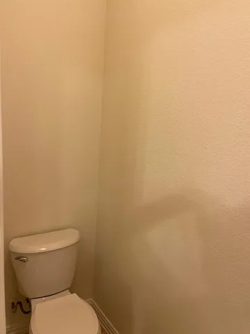 a white toilet sitting next to a white wall