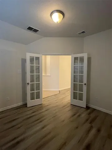 an empty room with wooden floor and windows