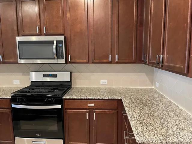 a kitchen with granite countertop wooden cabinets and a stove top oven