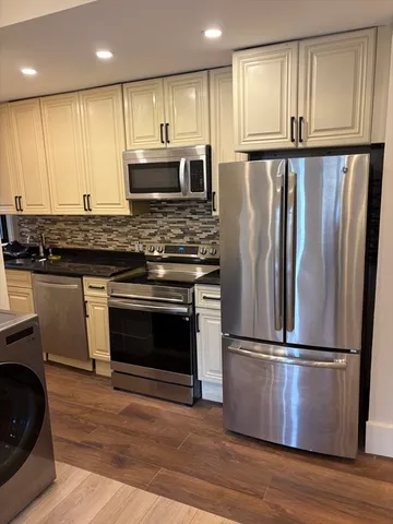 a kitchen with granite countertop stainless steel appliances and wooden floor