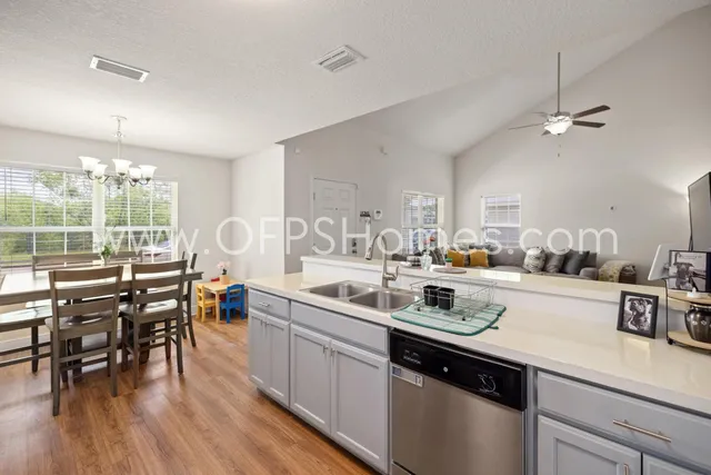 a kitchen with a sink a stove and chairs with wooden floor