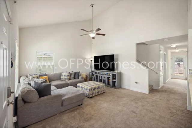 a living room with furniture a ceiling fan and a flat screen tv