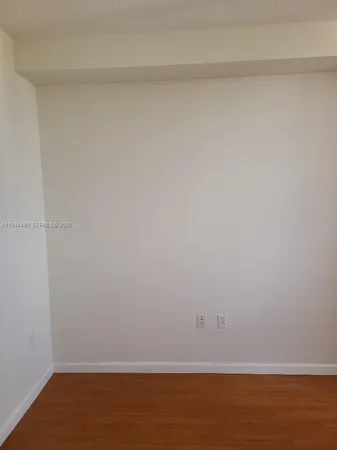a view of an empty room with wooden floor and closet