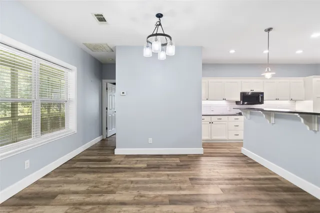 an empty room with wooden floor chandelier fan and windows
