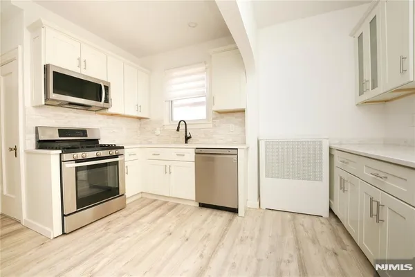 a kitchen with stainless steel appliances white cabinets a sink and a stove