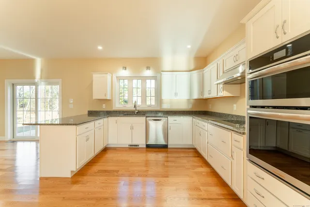 a large kitchen with stainless steel appliances kitchen island granite countertop a stove a sink and a microwave