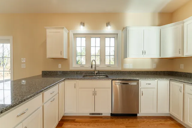 a kitchen with granite countertop white cabinets and a sink