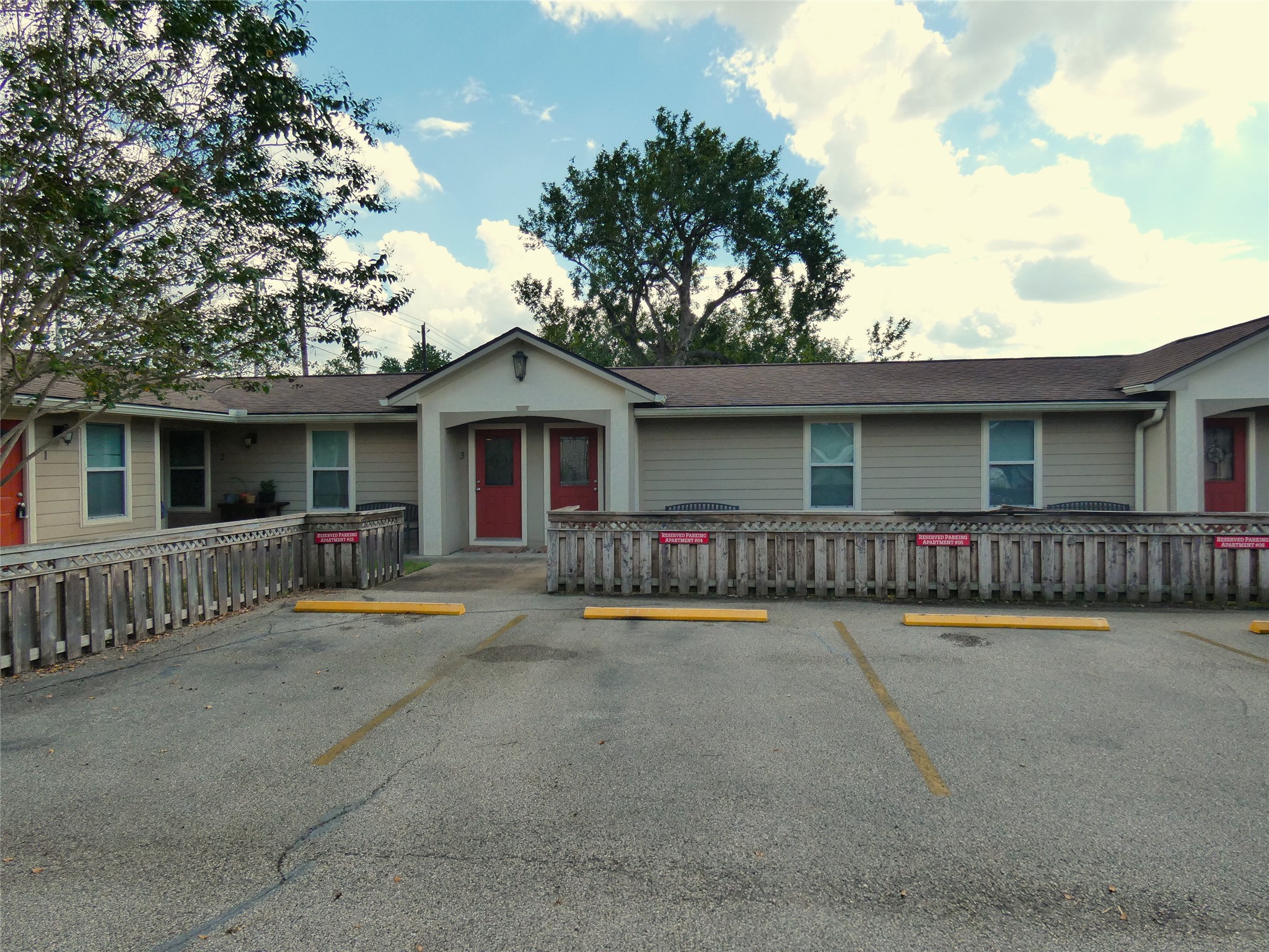 507 Houston Street, Unit 2 Rosenberg, TX 77471 - Photo 11 of 20 a view of a white house with large windows and a large tree with wooden fence