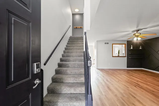 a view of an empty room with stairs and a ceiling fan