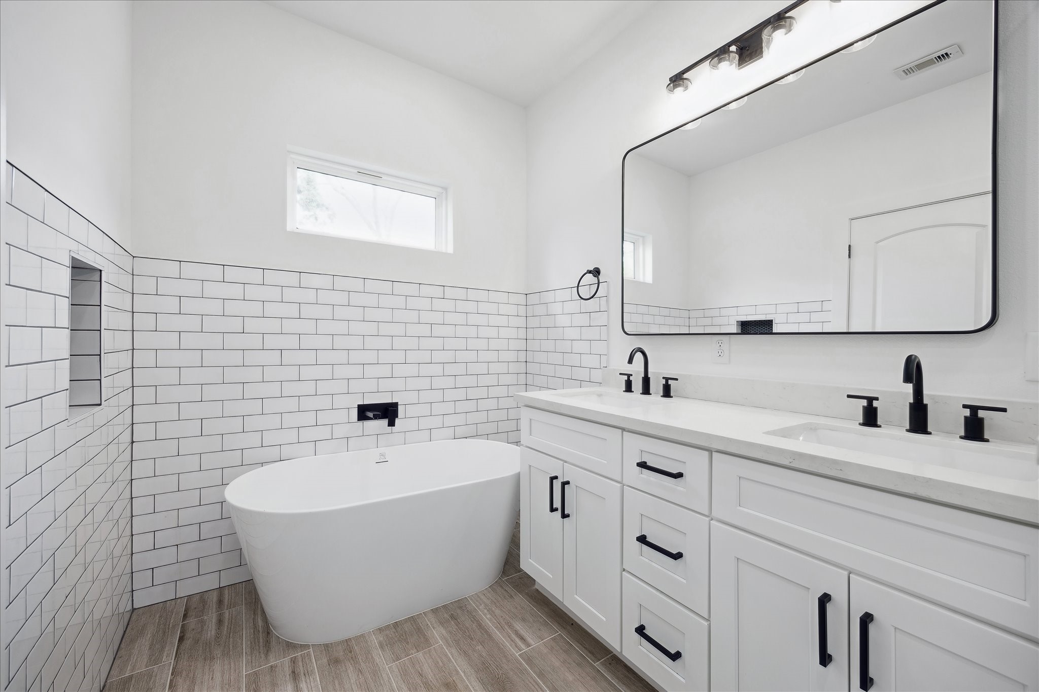 a bathroom with a double vanity sink a mirror and a bathtub