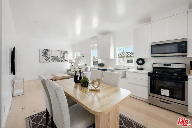 a kitchen with stainless steel appliances a stove a sink a microwave a dining table and chairs