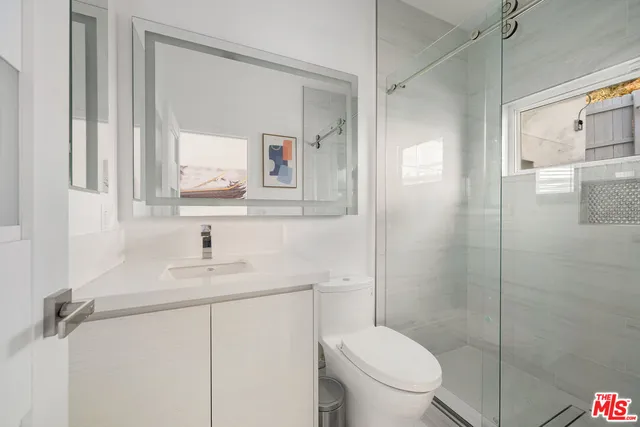 a bathroom with a toilet sink vanity shower and mirror