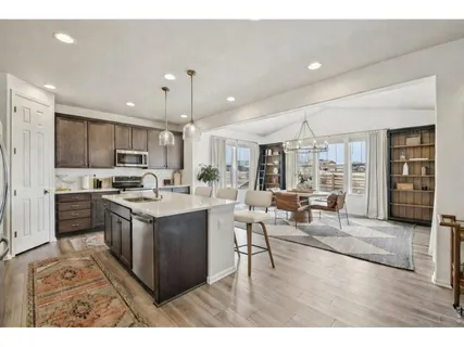 a kitchen with stainless steel appliances a refrigerator a stove a sink a dining table and chairs