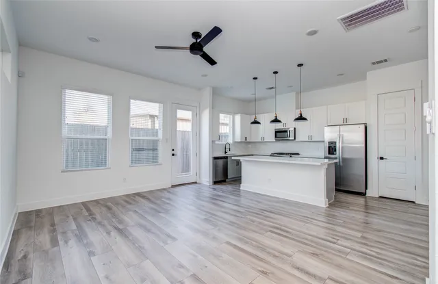 a large kitchen with stainless steel appliances kitchen island a large counter top and a wooden floors