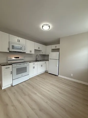 a kitchen with granite countertop white cabinets and white appliances