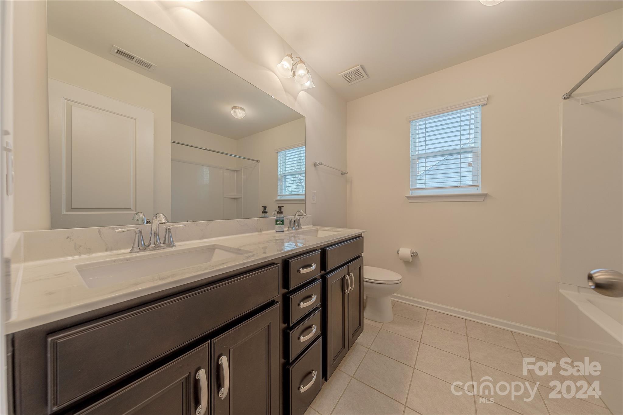 9604 Steele Meadow Road Charlotte, NC 28273 - Photo 34 of 46 a bathroom with a double vanity sink a toilet and a mirror