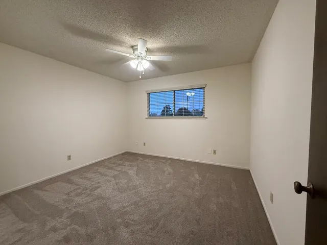 an empty room with a window and a fan